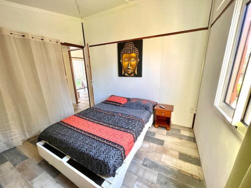 Schlafzimmer mit einem Bett mit einer Maske an der Wand in der Unterkunft Maison T3 près de l’aéroport in Sainte-Marie