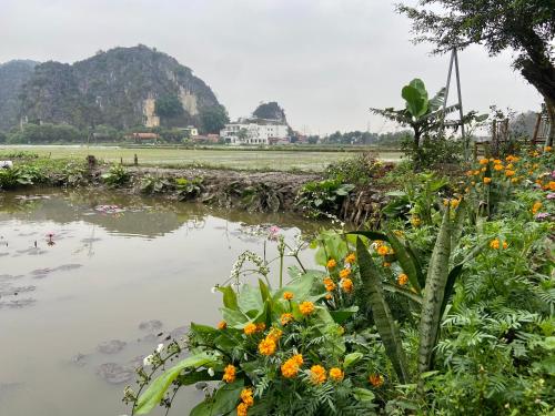 a garden with flowers in front of a body of water at Tam Coc Mountain View Homestay in Ninh Binh