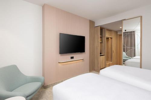 a bedroom with a bed and a tv on a wall at Courtyard by Marriott Cluj - Napoca Downtown in Cluj-Napoca