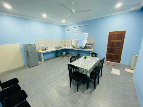 a kitchen and dining room with a table and chairs at Homestay Teratak Tamu Tawau in Tawau