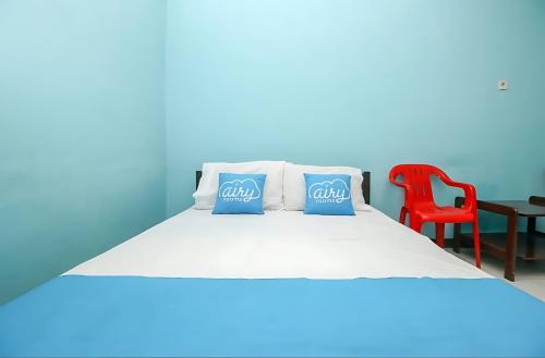 ein Bett mit zwei blauen Kissen und einem roten Stuhl in der Unterkunft Ambon Residence Syariah in Ambon