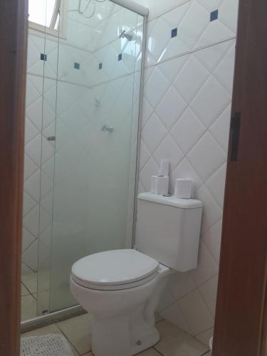 y baño blanco con aseo y ducha. en Apartamento Próximo ao Ribeirao Shopping, en Ribeirão Preto