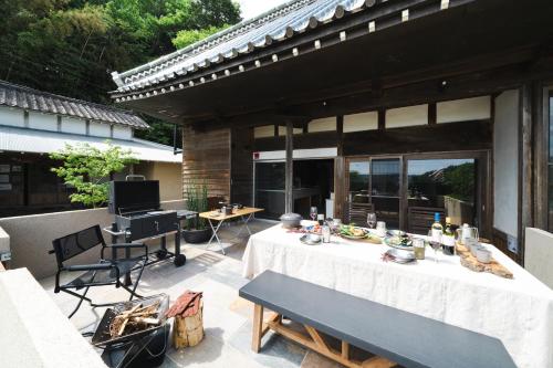 a patio with a table and chairs and a television at 一棟貸し古民家の宿まるがやつ in Ōtaki