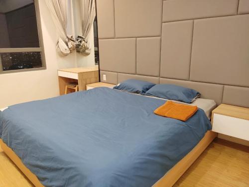 een slaapkamer met een bed met blauwe lakens en blauwe kussens bij MIO Masteri Thao Dien Serviced Apartment in Ho Chi Minh-stad