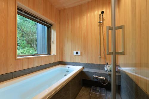 a bathroom with a bath tub and a window at 一棟貸し古民家の宿まるがやつ in Ōtaki