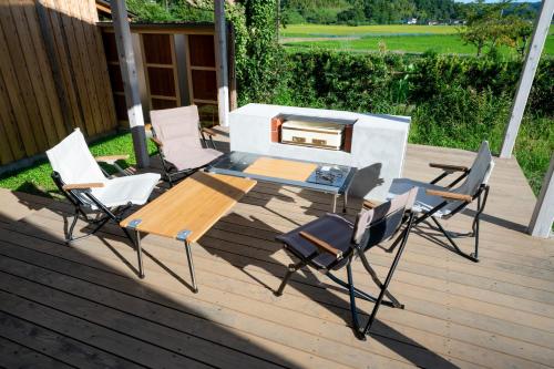 a group of chairs and a table on a deck at 一棟貸し古民家の宿まるがやつ in Ōtaki