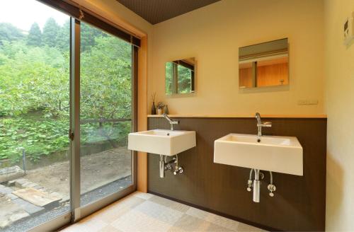 two sinks in a bathroom with a window at 一棟貸し古民家の宿まるがやつ in Ōtaki
