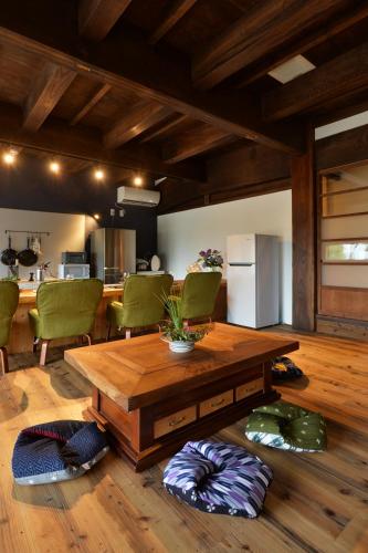 a living room with a wooden table and green chairs at 一棟貸し古民家の宿まるがやつ in Ōtaki