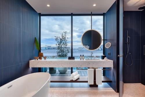 a bathroom with a tub and a sink and a mirror at Dorothea Hotel, Budapest, Autograph Collection in Budapest