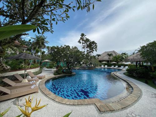 una piscina en un complejo con sillas y árboles en Medewi Bay Retreat, en Pulukan