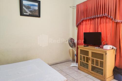 a bedroom with a bed and a television on a cabinet at Hotel Jaya Wisata RedPartner in Sungaipenuh