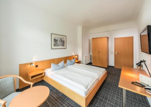 a hotel room with a bed and a desk at City Hotel in Eisenach
