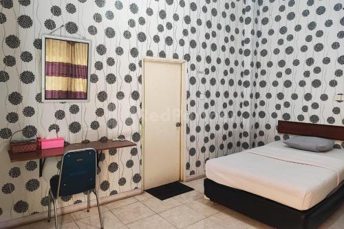 een slaapkamer met een bed, een spiegel en een stoel bij Hotel Jaya Wisata RedPartner in Sungaipenuh