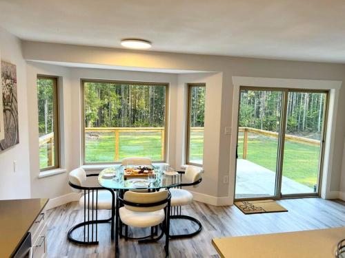 a dining room with a table and chairs and windows at Nature Lovers’ Paradise in Nanaimo