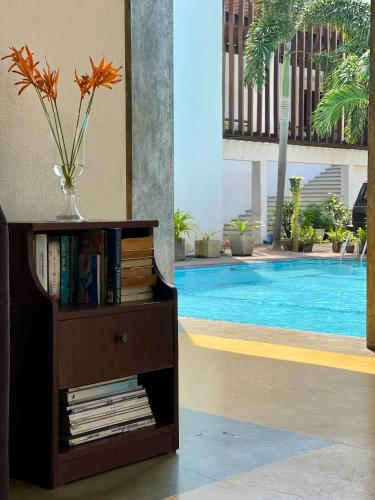 a book shelf with a vase of flowers on it next to a pool at Olanro Hotel Negombo in Negombo