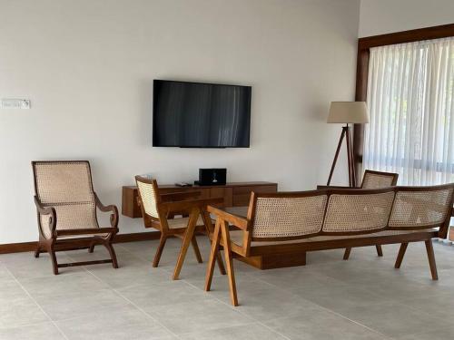 een woonkamer met een tafel en stoelen en een televisie bij Lake Round Luxury House in Kurunegala