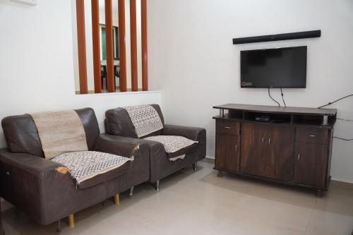 a living room with a couch and a tv at Redstone House by Oxystays Hospitality in Ganpatipule