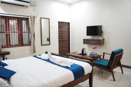 a bedroom with a bed and a desk and a television at Redstone House by Oxystays Hospitality in Ganpatipule