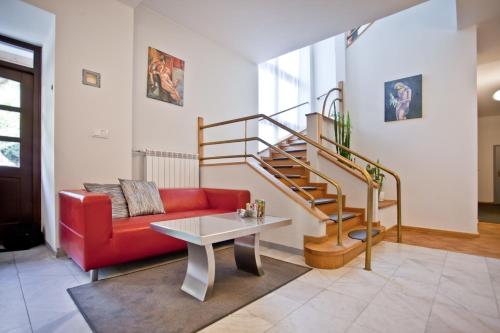 a living room with a red couch and a staircase at Urocza Art Pensjonat in Krynica Zdrój