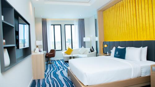 Un dormitorio con una gran cama blanca y una pared amarilla en Savan Resorts en Savannakhet