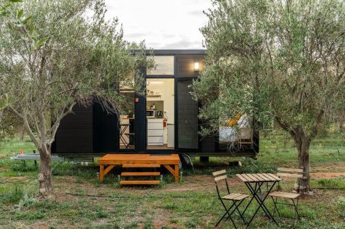 een zwart tiny house met een picknicktafel en bomen bij Olive Grove Retreat 1 in Lake Boga