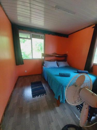 een slaapkamer met oranje muren en een bed met een ventilator bij Marupo Room in Fare