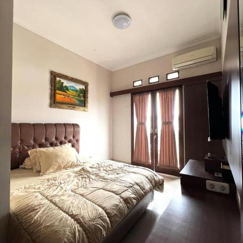 a bedroom with a large bed and a television at Hens Guesthouse Syariah in Gadobangkong