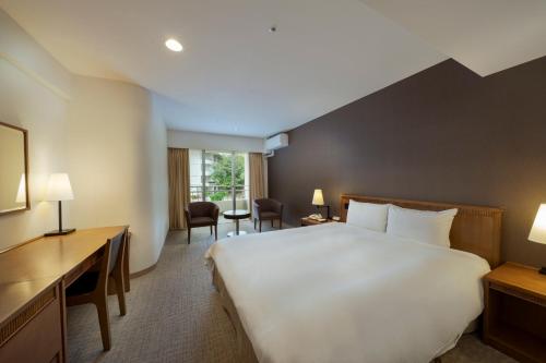 ein Hotelzimmer mit einem großen Bett und einem Schreibtisch in der Unterkunft EM Wellness Kurashinohakko Lifestyle Resort in Kitanakagusuku