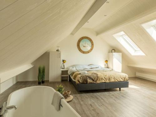 een slaapkamer op zolder met een bed en een bad bij Chill Op Ameland in Ballum
