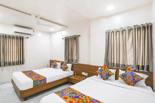 two beds in a room with white walls and windows at Hotel D Grand in Shirdi