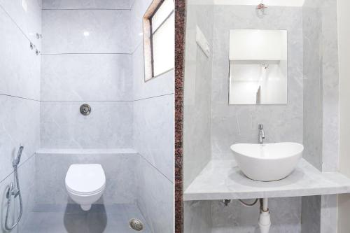 a white bathroom with a sink and a toilet at Hotel D Grand in Shirdi