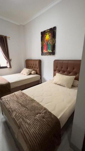 a bedroom with two beds and a painting on the wall at Hens Guesthouse Syariah in Gadobangkong