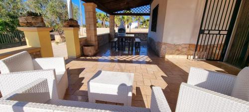 an outdoor patio with white chairs and a table at Villa Marchese with private pool in Gallipoli