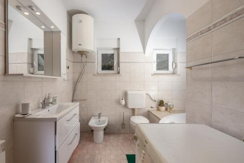 uma casa de banho branca com um lavatório e um WC em Apartman Lavanda em Kostrena