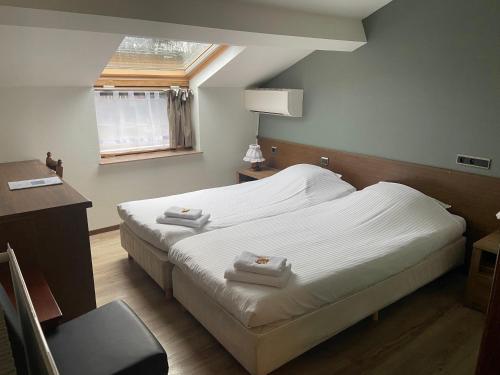 1 dormitorio con 2 camas, escritorio y ventana en Hotel Monika, en Zutendaal