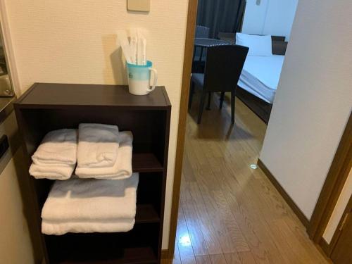 ein Badezimmer mit Handtüchern auf einem Regal mit einem Spiegel in der Unterkunft AO Dazaifu / Vacation STAY 61720 in Chikushino