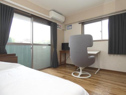 een slaapkamer met een bed, een stoel en ramen bij AO Dazaifu - Vacation STAY 93787 in Chikushino