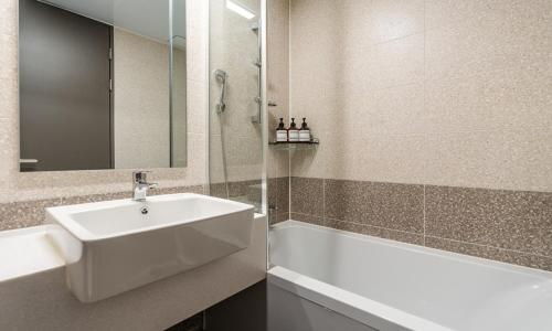 a bathroom with a sink and a bath tub at Radiant Nampo Hotel in Busan