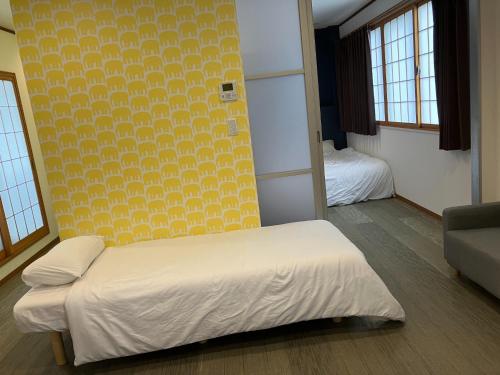 AO Dazaifu / Vacation STAY 61736 في Chikushino: غرفة نوم بسرير وجدار اصفر