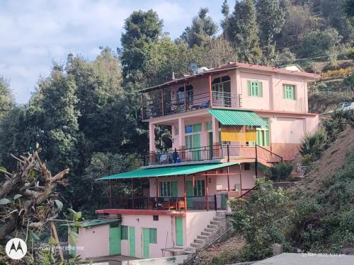 a large pink house on a hill with trees at The Moon Light Home stay in Bhīm Tāl
