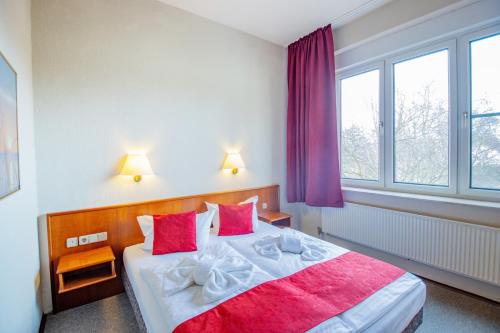 a bedroom with a large bed with red and white pillows at Seehotel Brandenburg an der Havel in Brielow