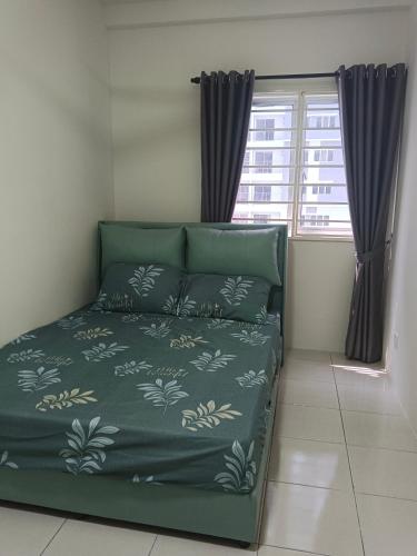 a bedroom with a green bed with a window at Homestay Melody Puncak Alam in Bandar Puncak Alam