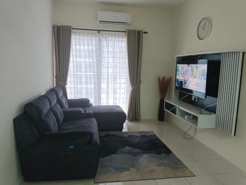 a living room with a couch and a flat screen tv at Homestay Melody Puncak Alam in Bandar Puncak Alam