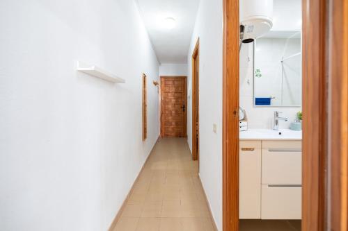 a hallway leading to a bathroom with white cabinets and a sink at PRIMERA LINEA Playa Romana Frontal al Mar ALBERT VILLAS in Alcossebre
