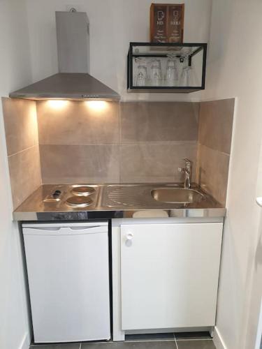 une petite cuisine avec un évier et une cuisinière dans l'établissement Bel appartement avec patio, à Villejuif