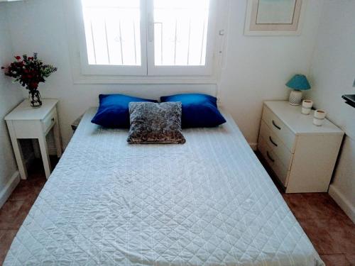 um quarto com uma grande cama branca com almofadas azuis em casatrace em Ciudad Quesada