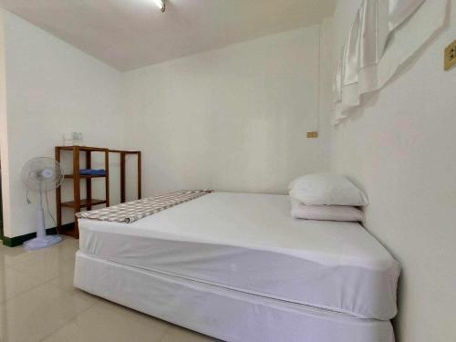 a bedroom with a white bed and a fan at Ln House Chiang Mai in Chiang Mai