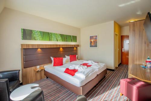 a hotel room with a large bed with red pillows at Seehotel Brandenburg an der Havel in Brielow