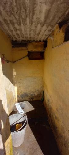 een kleine badkamer met een toilet en een emmer bij Harish Homestay in Kapkot