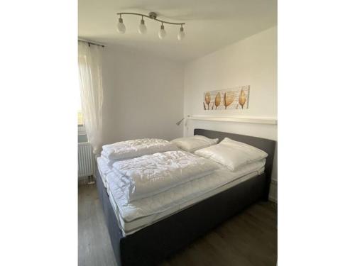 a white bedroom with a bed with white sheets at Holiday home Lilly in Staberdorf